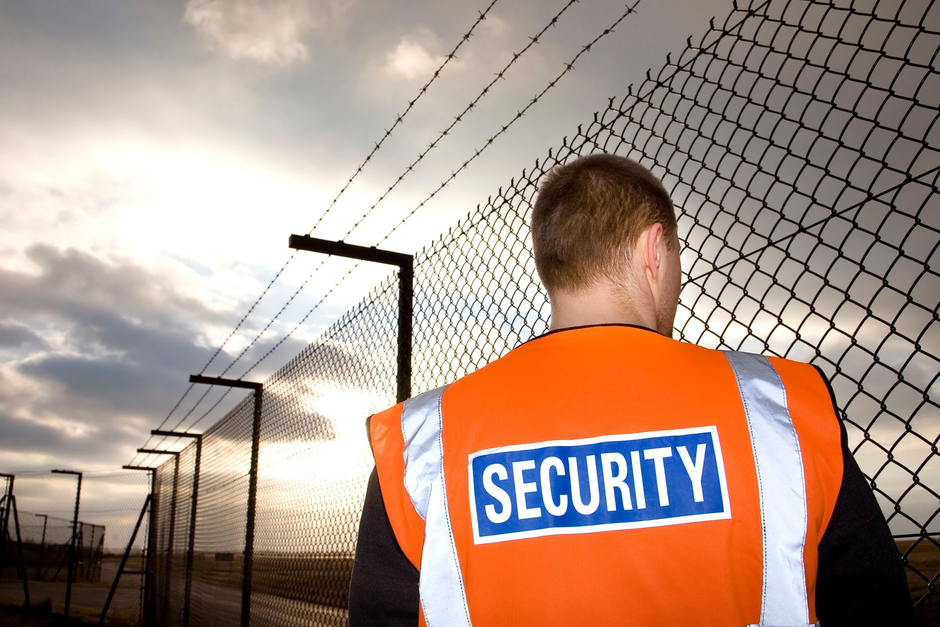 Security guard on patrol near tall fence